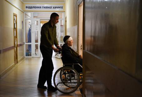 A soldier pushes a wheelchair with an injured Ukrainian soldier in a military hospital in Lviv on March 01, 2022